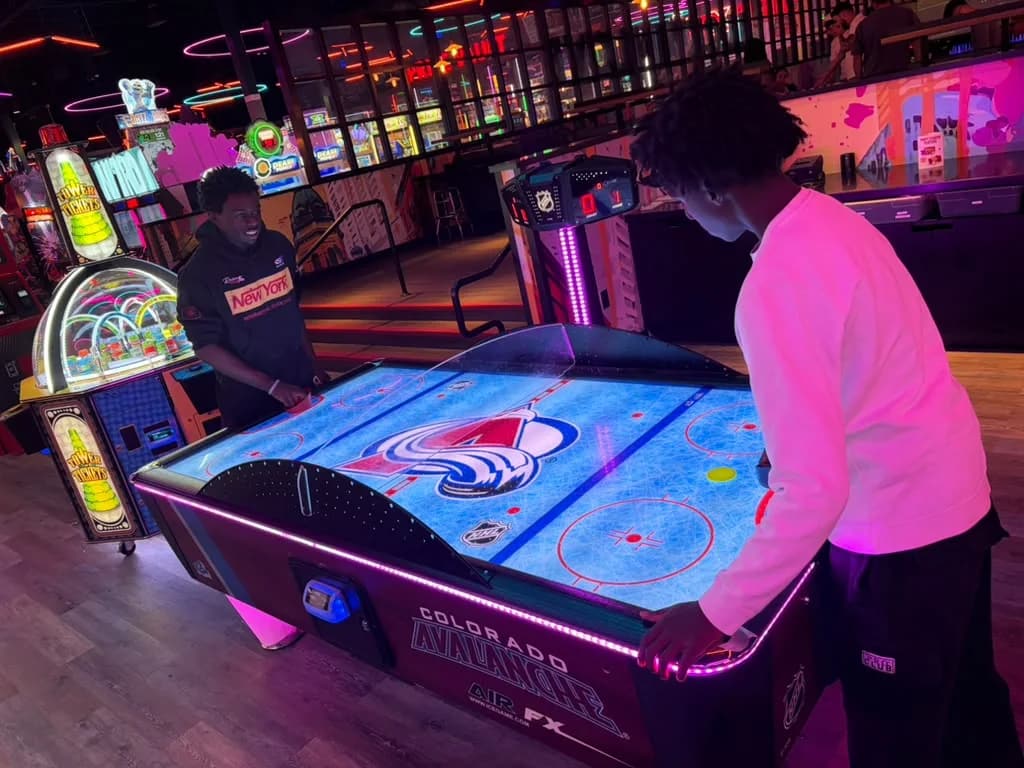 MHC youth members playing air hockey on a Colorado Avalanche themed table